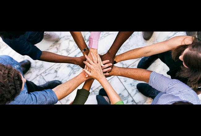 Group of people lined up in a circle and put their hands on top of each other.