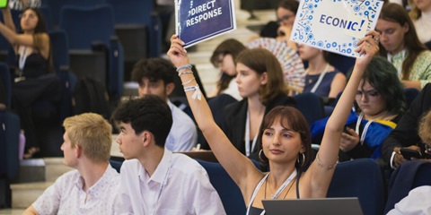 Young people hold up signs in a lecture hall